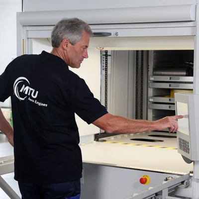 Ein Mitarbeiter aus dem Bereich Logistik und Vorbereitung entnimmt Messmittel aus dem Paternoster.
